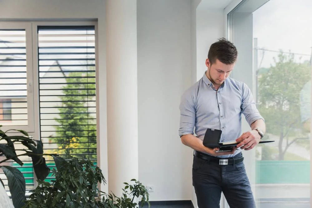 Mand i skjorte læser på en tablet i et lyst kontor